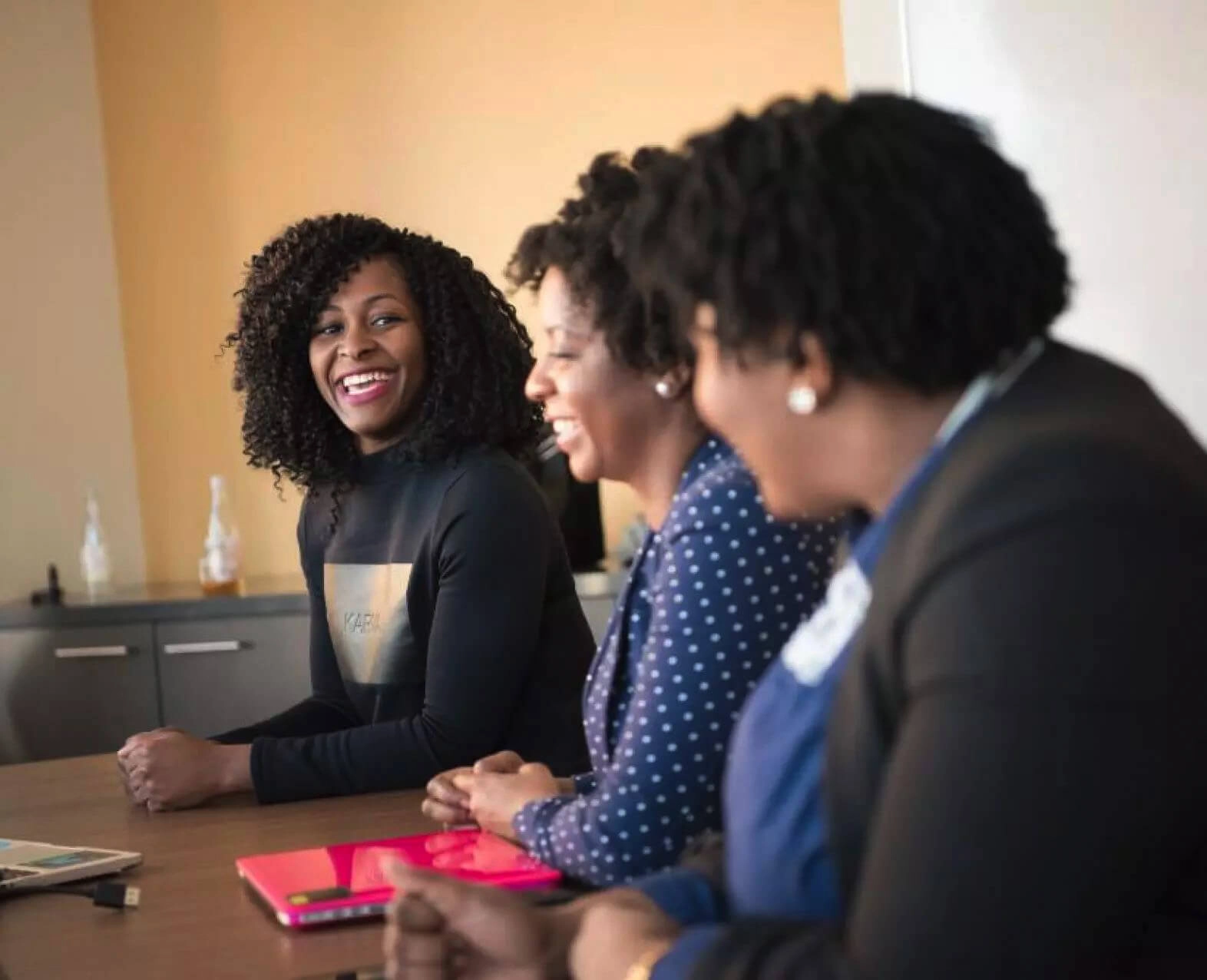 Three women smiling and chatting during a business meeting. (photo)