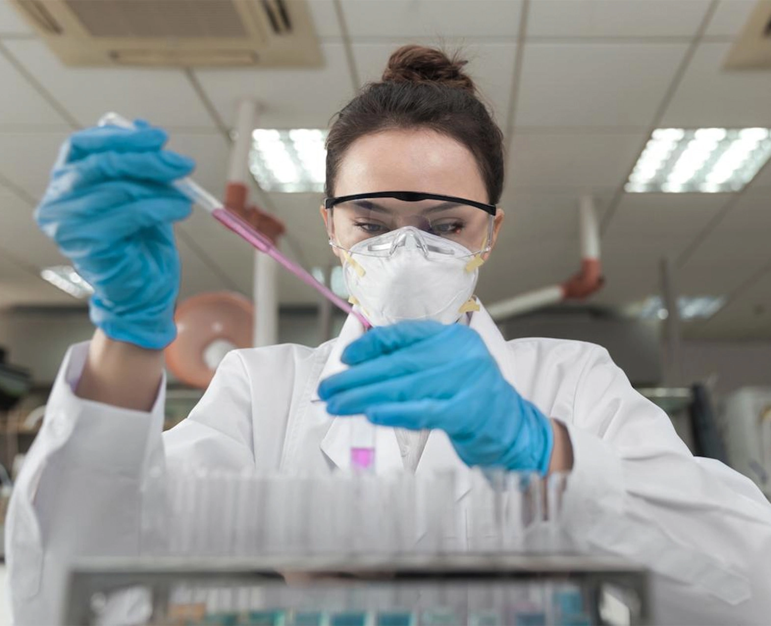 A woman scientist working in a lab with safety goggles, mask, and gloves. (photo)