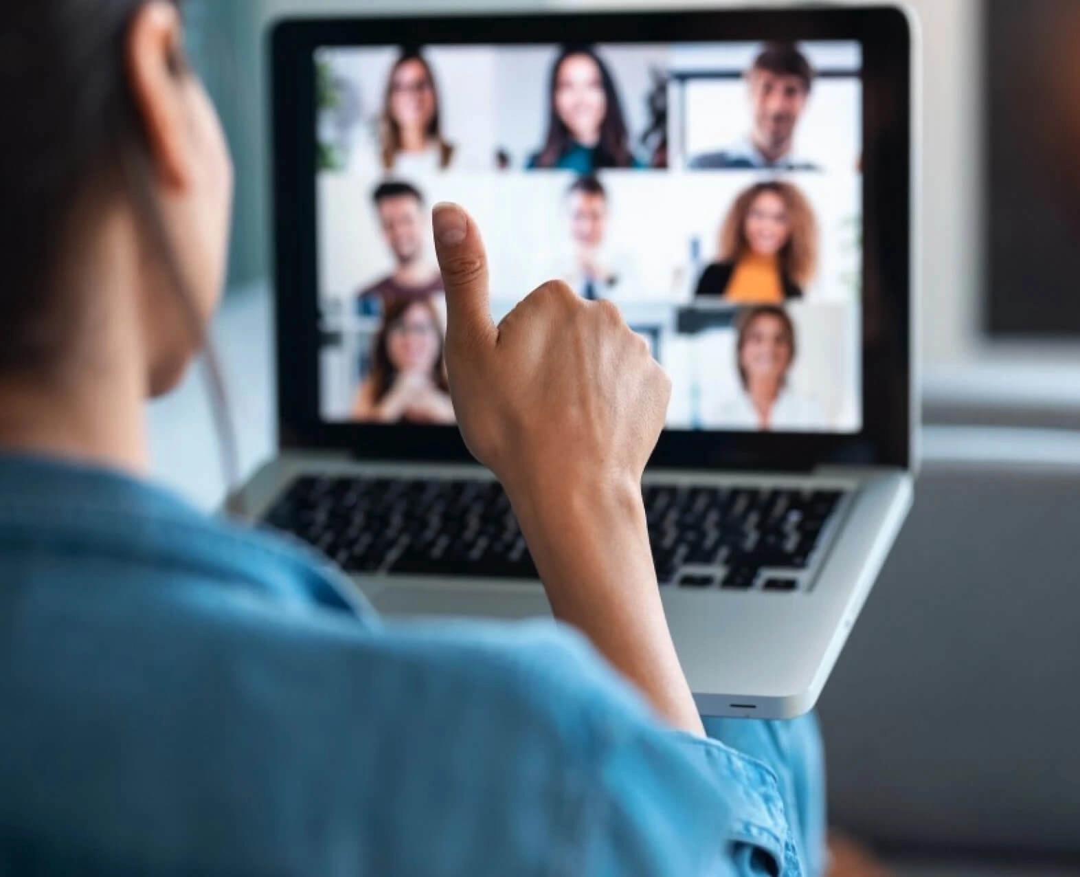 A person giving a thumbs-up during a video conference on a laptop. (photo)