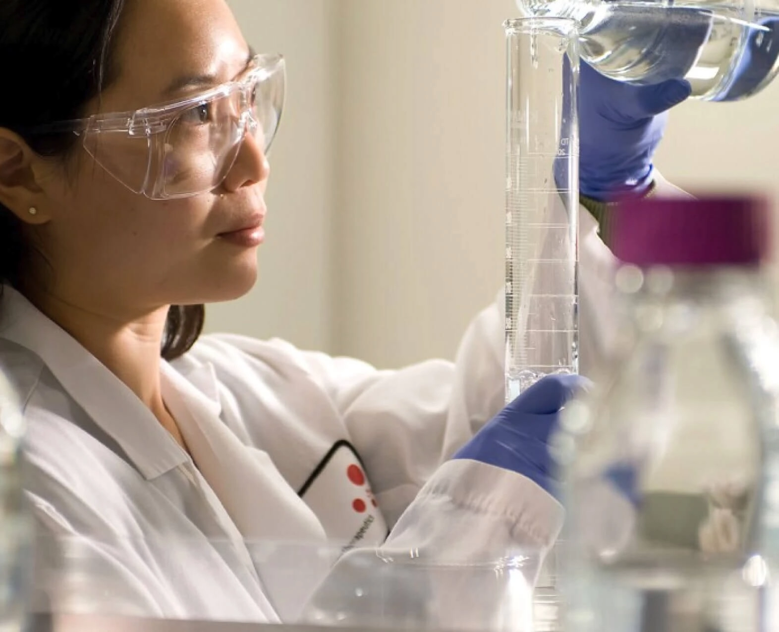 A scientist wearing safety goggles working with lab equipment. (photo)