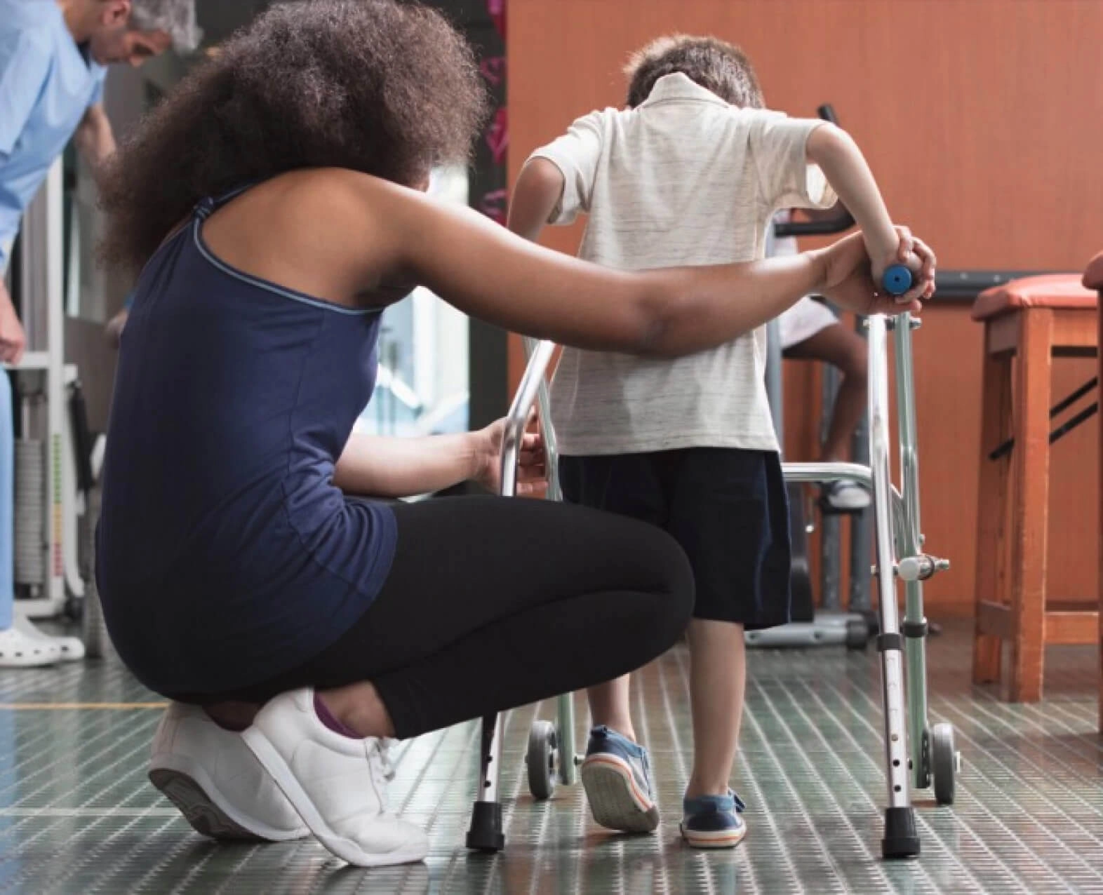 A woman helping a child to walk using a walker (photo)